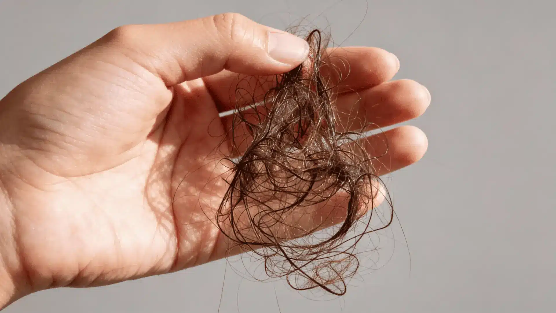 Close-up of a person holding clumps of hair after hair loss dur to hrt emphasizing loose strands, natural texture, and realistic detail