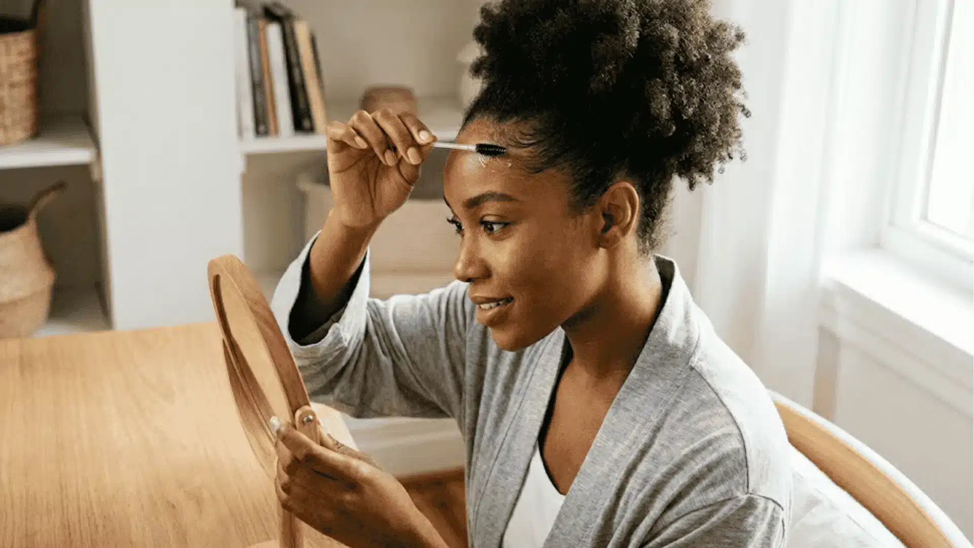 A woman at a table brushes her hair, showcasing different techniques for properly laying edges