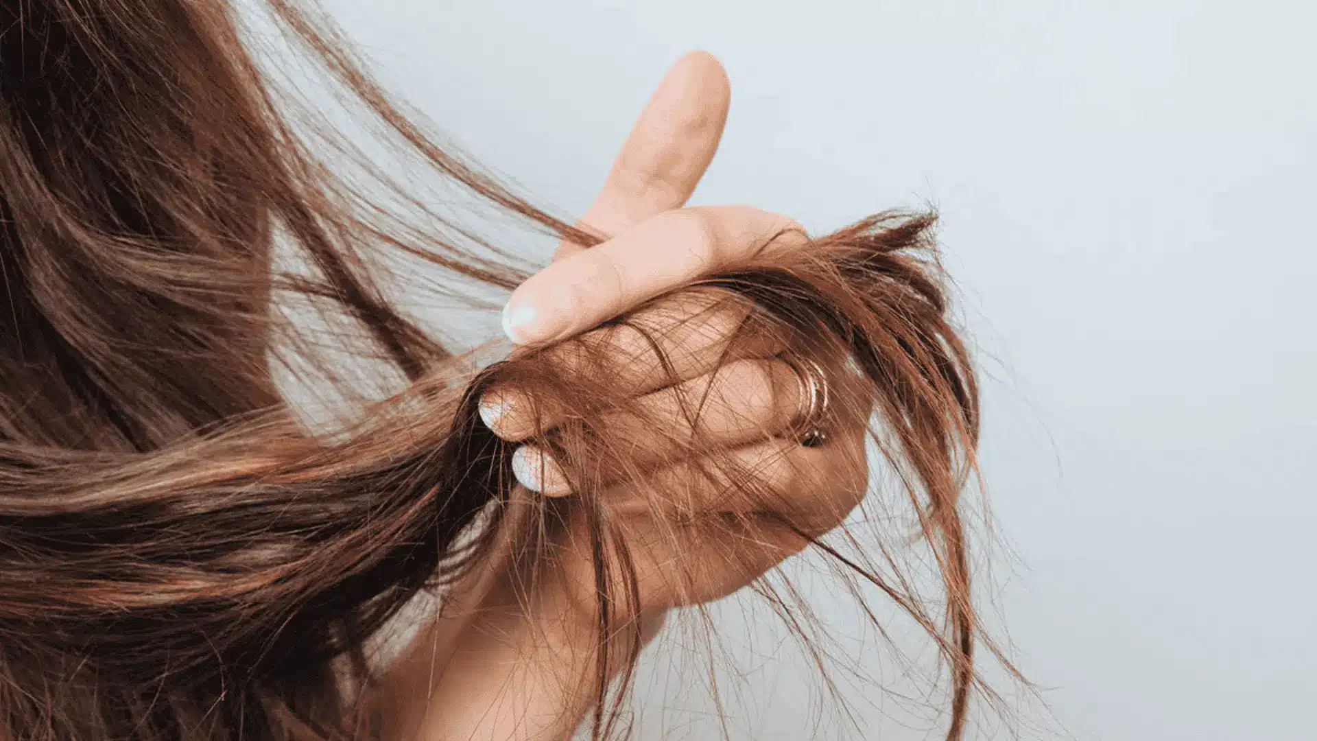 A woman lifting her hair, reflecting on the concept of low porosity in hair health