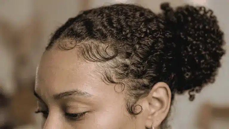 A woman with curly hair demonstrating edge control tips for achieving sleek hairlines