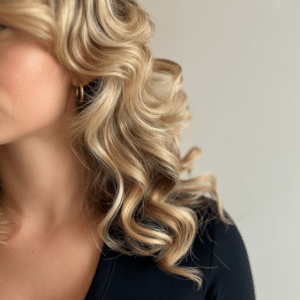A woman with long blonde hair in overnight curls, dressed in a black top
