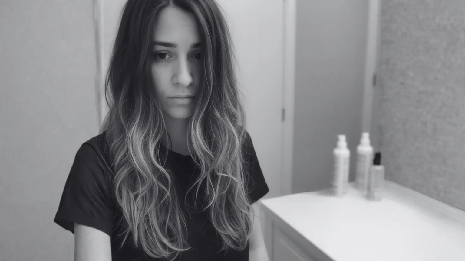 A woman with long hair contemplating the risks and reversal of balayage hair treatment