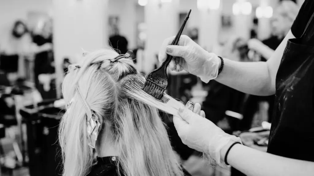 A woman with long wavy hair from back view demonstrating a hair coloring techniques applied on her hair