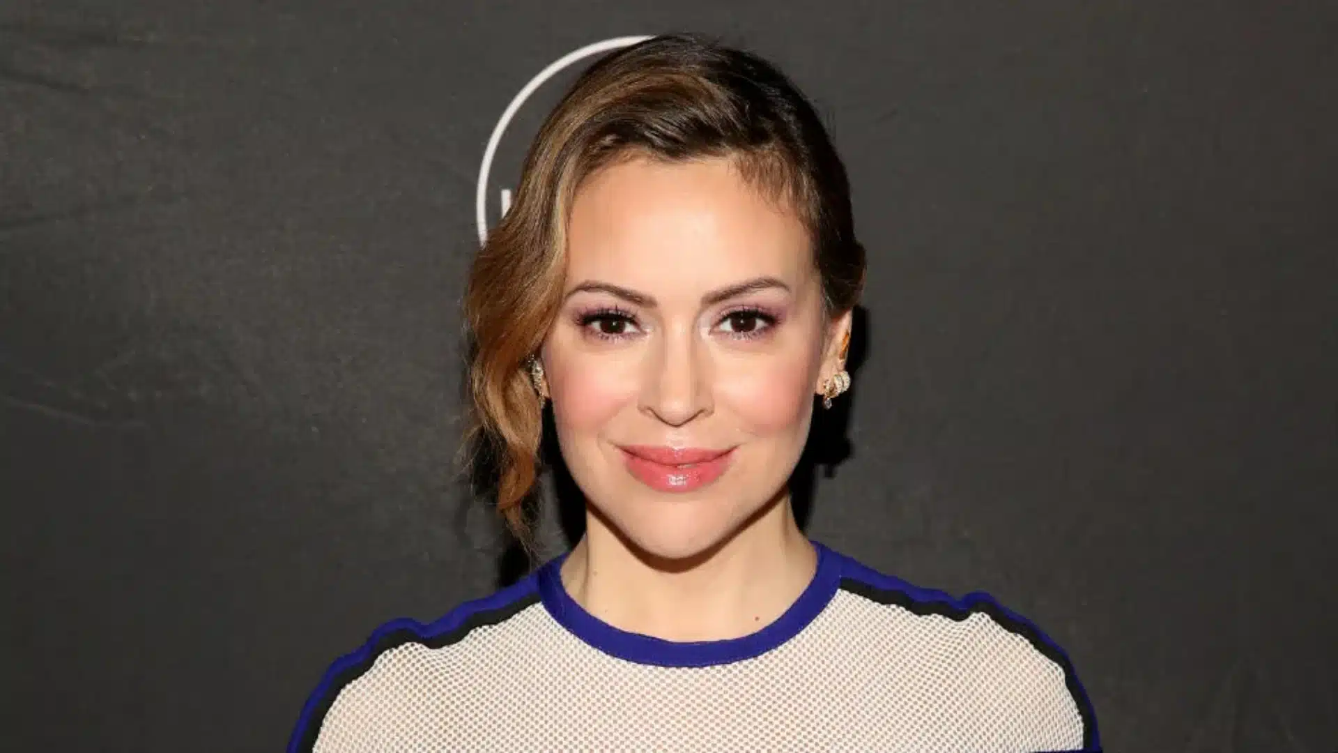 Alyssa Milano poses for the camera in a blue and white dress, showcasing her healthy hair