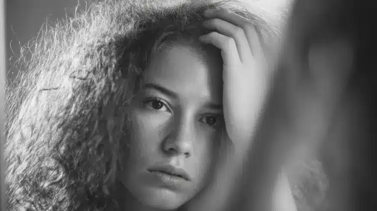 Woman with curly hair in mirror showing Signs of Overwashing Hair and How to Fix Damage Fast