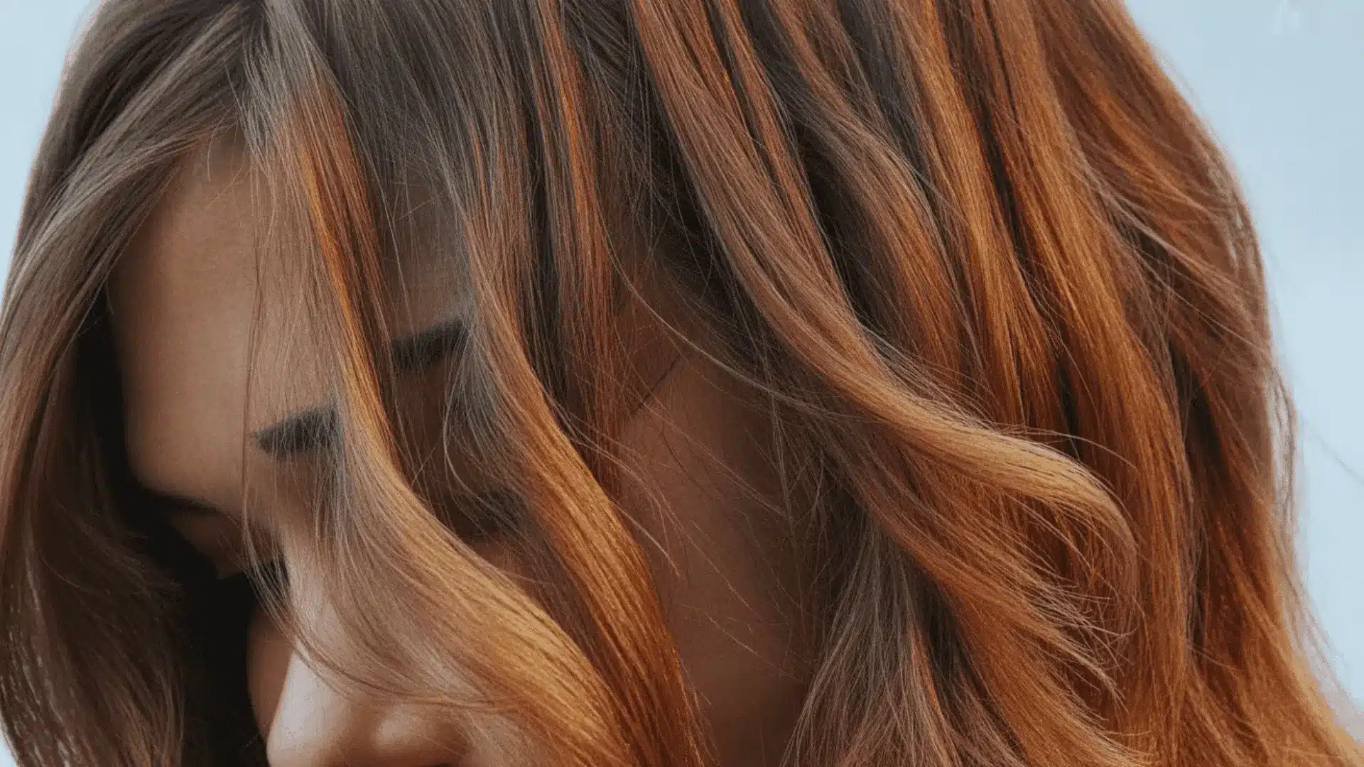 brassy orange tones appearing in brown hair strands when cool toned lowlights begin to fade