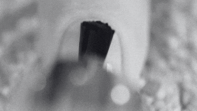 A close-up of a black and white image showing the application of a base coat on a nail