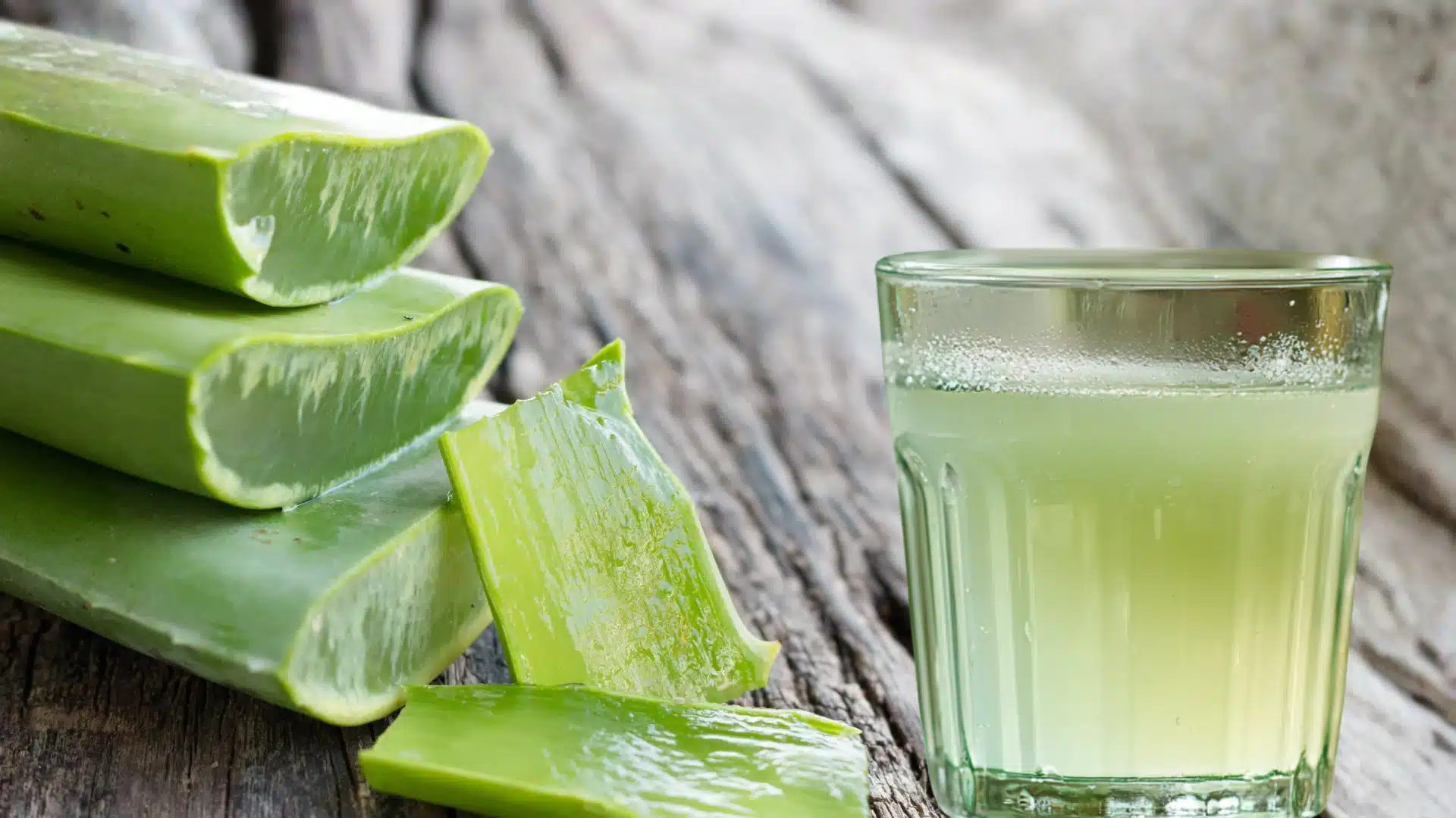 glass with ice water aleovera slices on a marble surface in front of a window with soft green sunlight