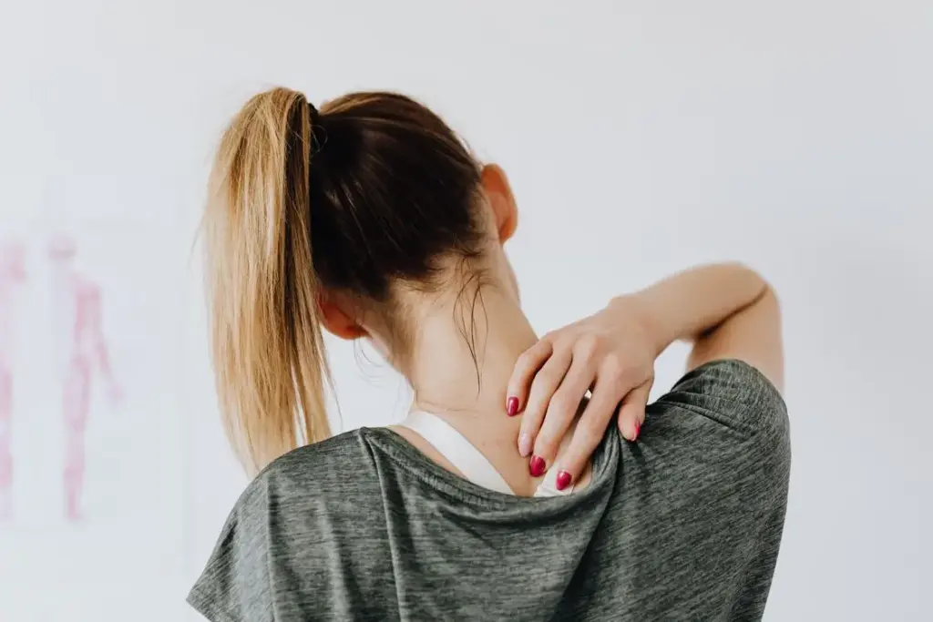 Woman touching her neck with one hand in bright indoor setting