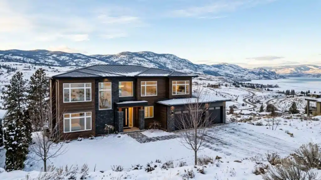 exterior view of a Kelowna home with large vinyl windows during winter with snow-covered okanagan hills in the background