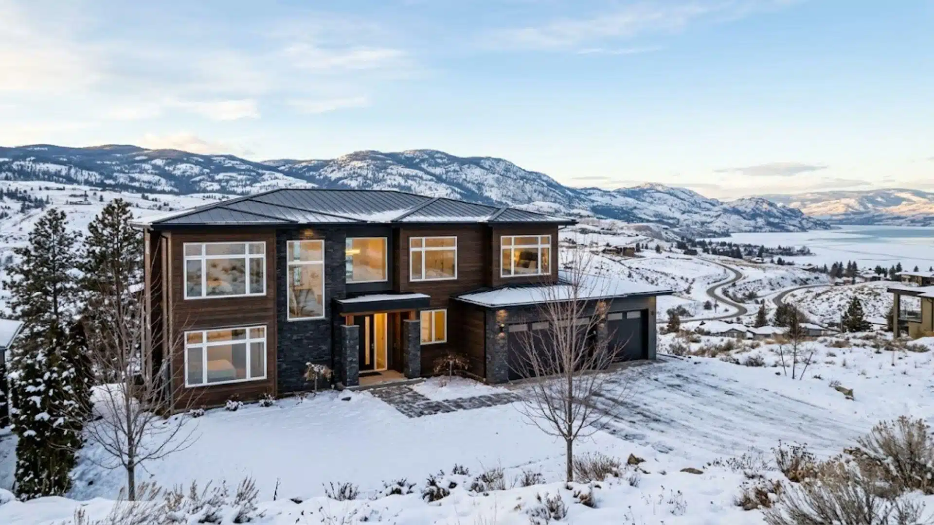 exterior view of a Kelowna home with large vinyl windows during winter with snow-covered okanagan hills in the background