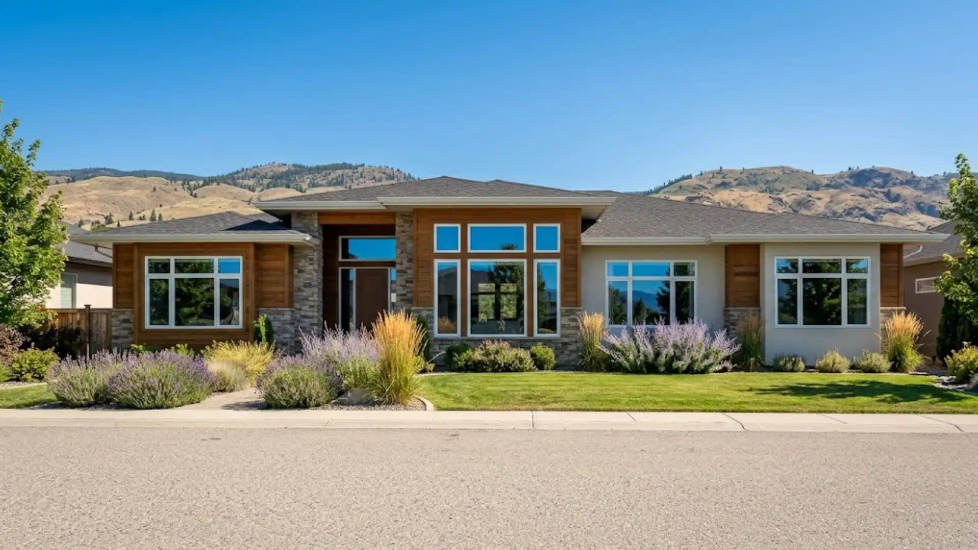 exterior of a contemporary Kelowna home with large picture and casement windows under a clear okanagan summer sky
