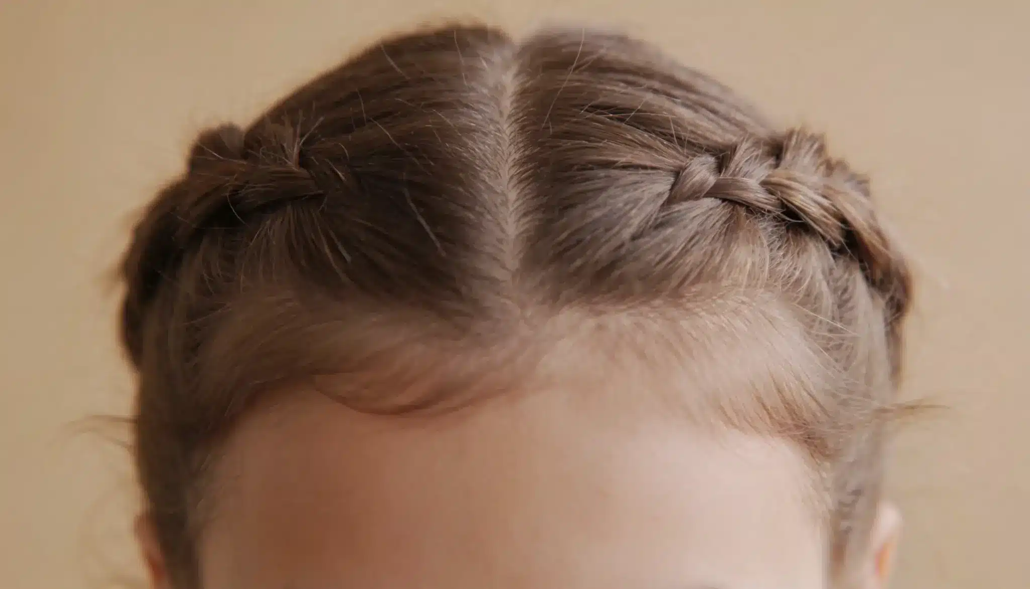 Close-up of loose braided pigtails with a center part, styled gently to reduce tension on the hairline.