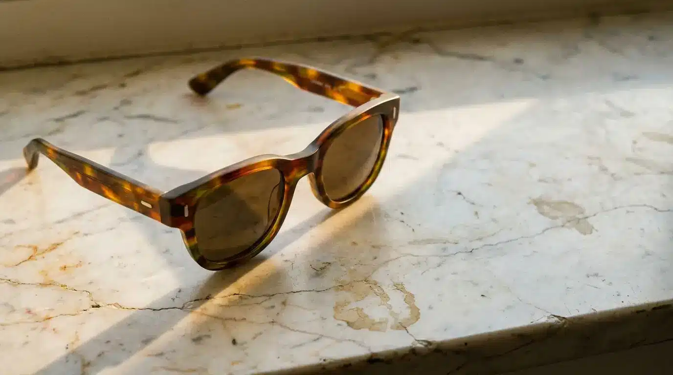 Tortoiseshell sunglasses resting on a marble windowsill in soft natural light