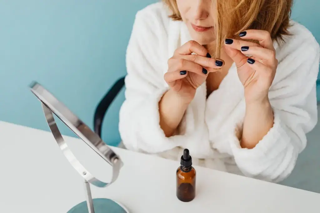 Woman in white robe applying hair oil in bright bathroom setting