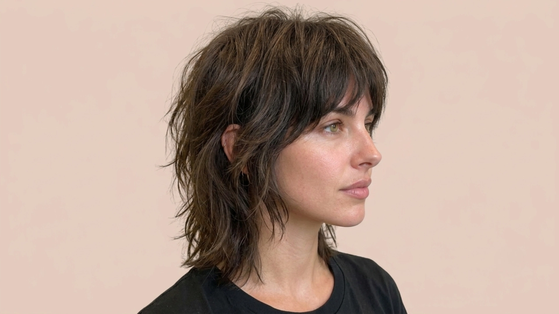 A woman with a shag cut, featuring short, dark brown hair styled in layers.