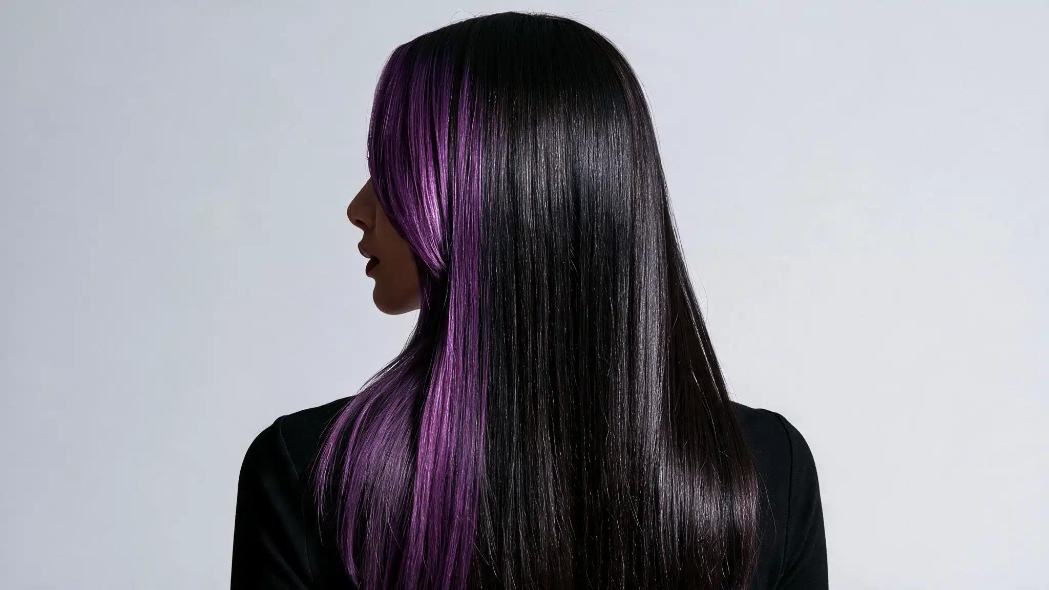 A woman with long black hair adorned with vibrant purple highlights around her face.