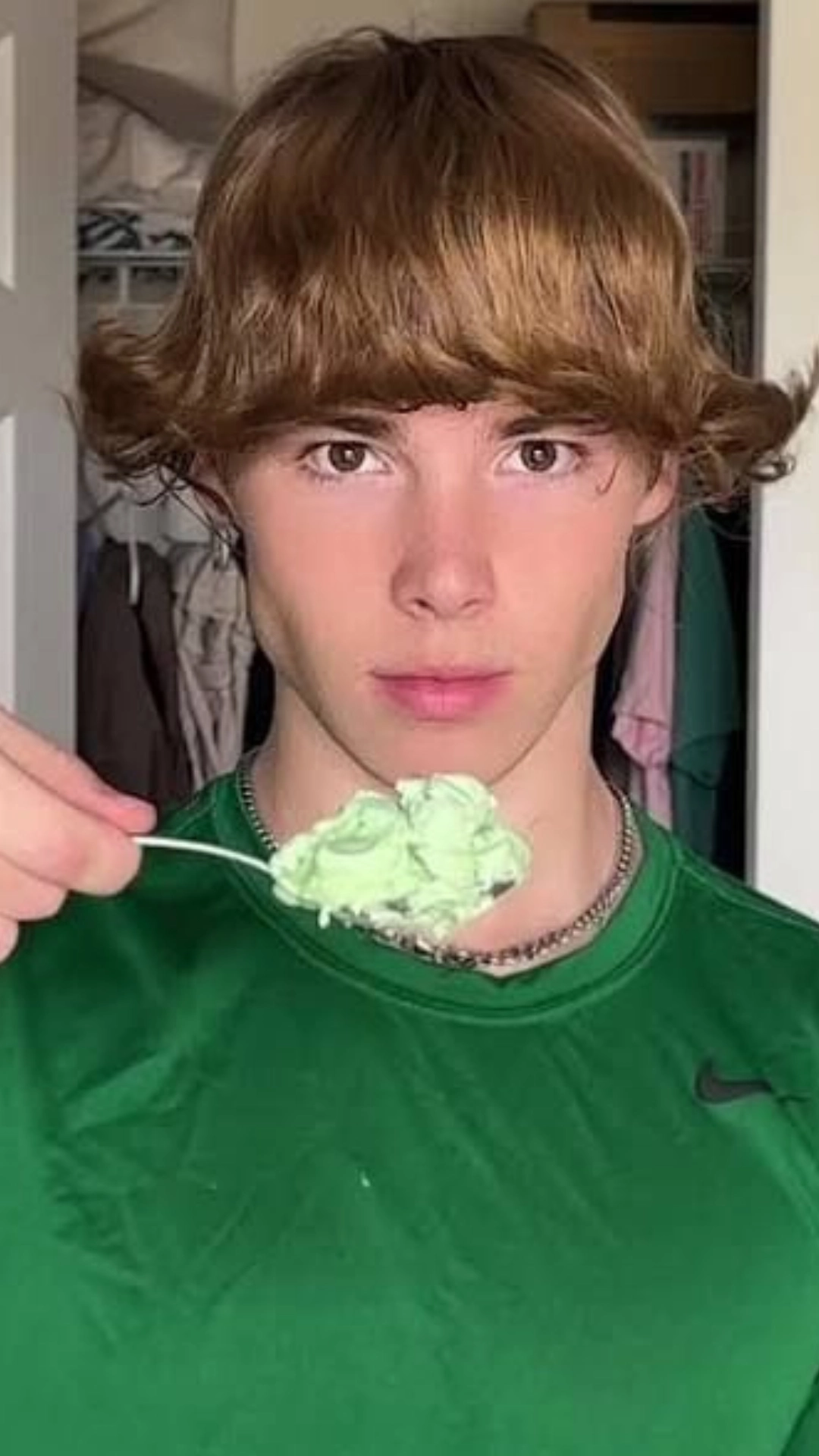A young man in a green shirt savors ice cream, featuring a playful ice cream scoop haircut.