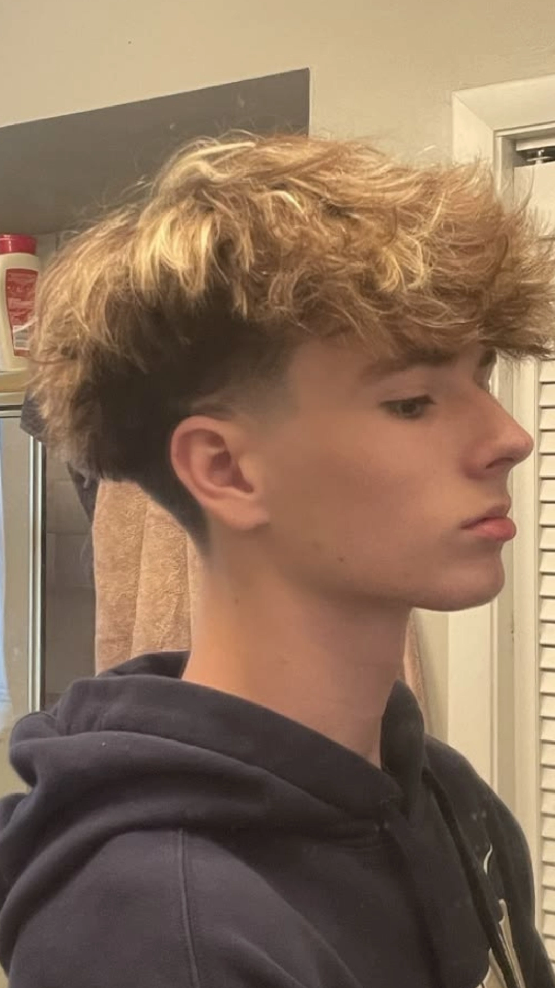 A young man with a very short haircut featuring a wavy fringe style.