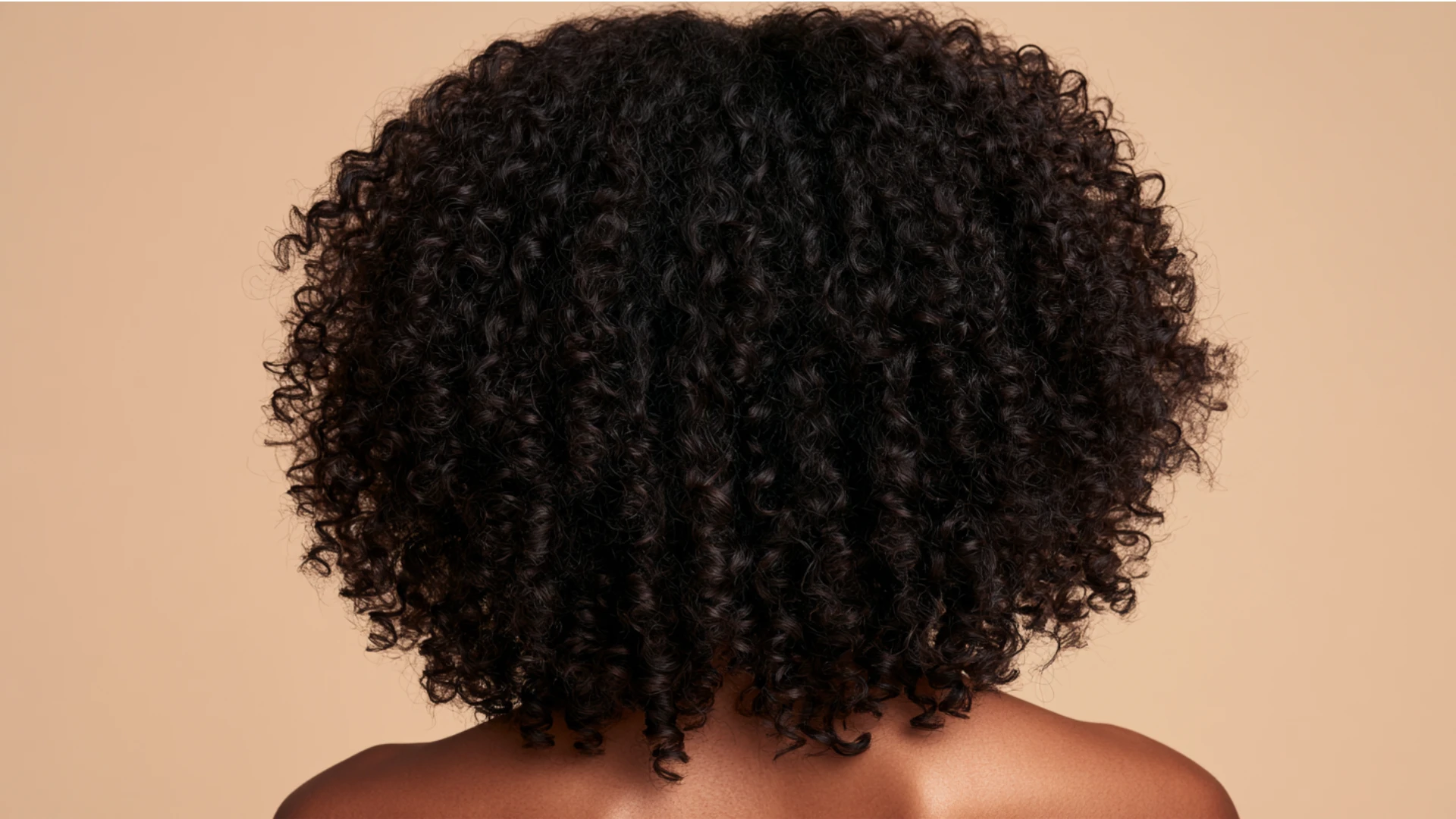 Back view of an African American woman with curly hair, showcasing her Type 4A coils in natural texture.