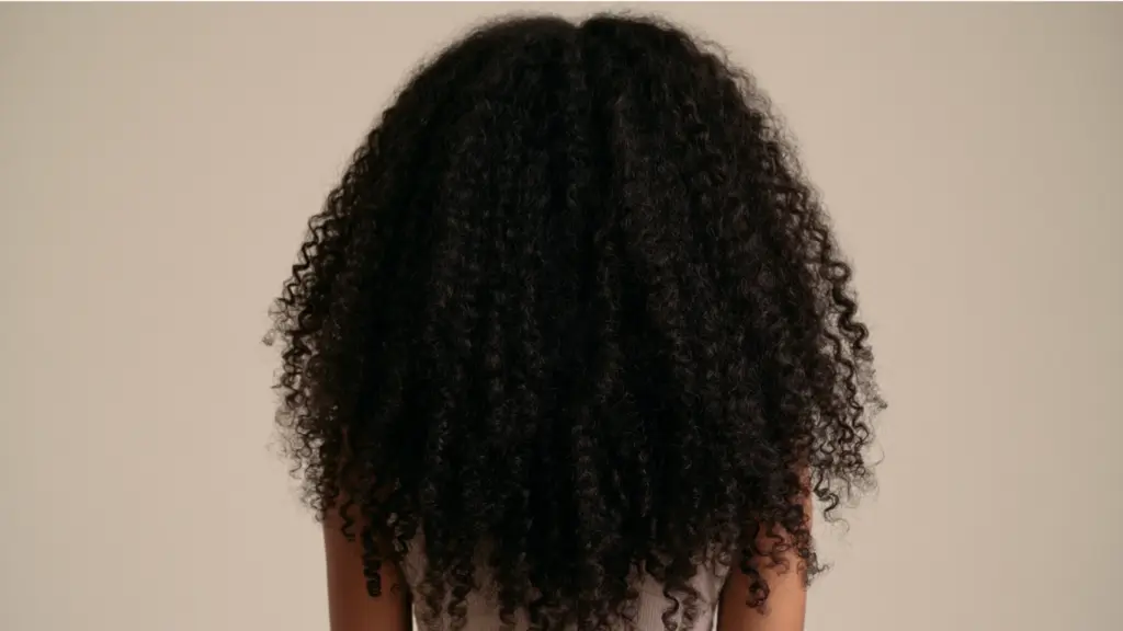 A woman with beautifully defined, long coily hair, highlighting the richness and bounce of her coils.
