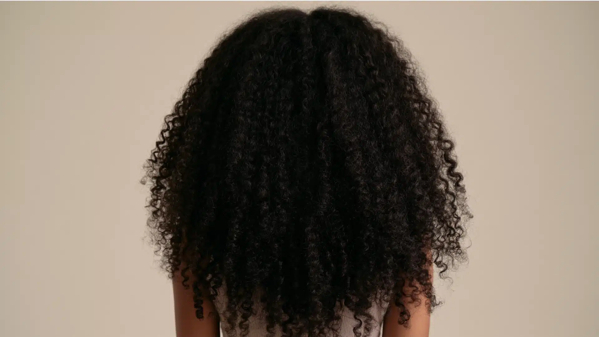 A woman with beautifully defined, long coily hair, highlighting the richness and bounce of her coils.
