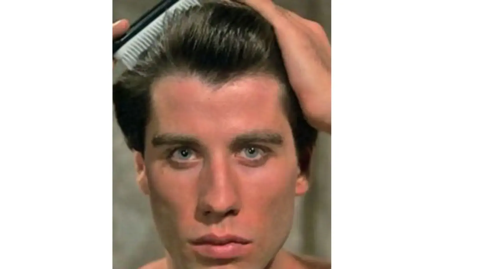 John Travolta in the movie Saturday Night Fever, combing his hair, his eyes are blue-green.