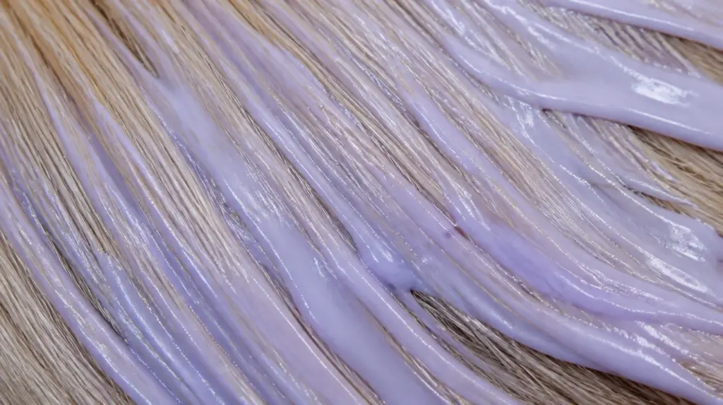 A closeup of blonde hair with toner applied, and spread on it.