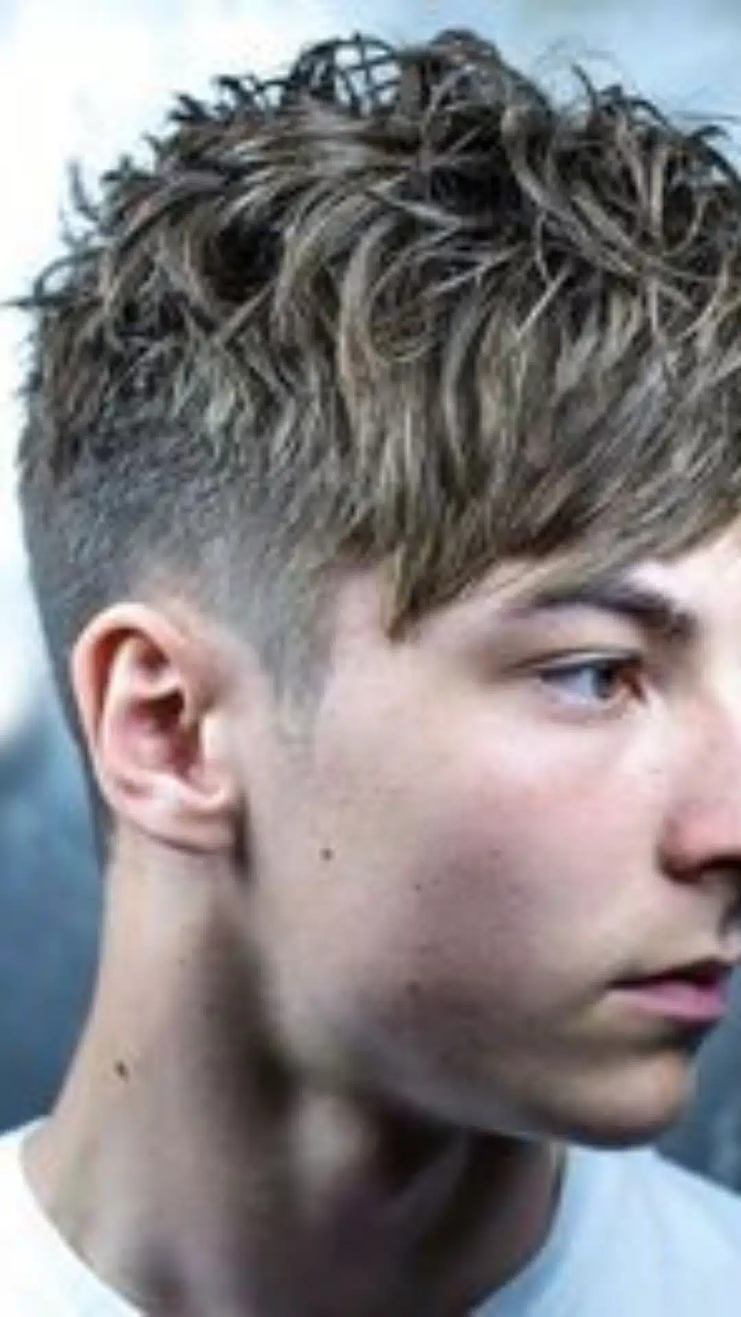 Messy textured fringe haircut with a high fade shown from the side with natural volume and a clean modern finish