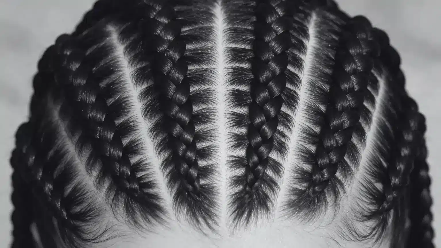 A close-up of a woman with intricate pop smoke braids, reflecting the popular hairstyle associated with Pop Smoke.