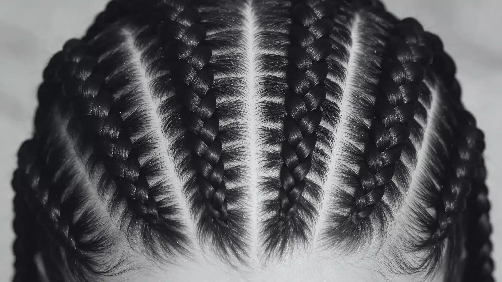 A close-up of a woman with intricate pop smoke braids, reflecting the popular hairstyle associated with Pop Smoke.