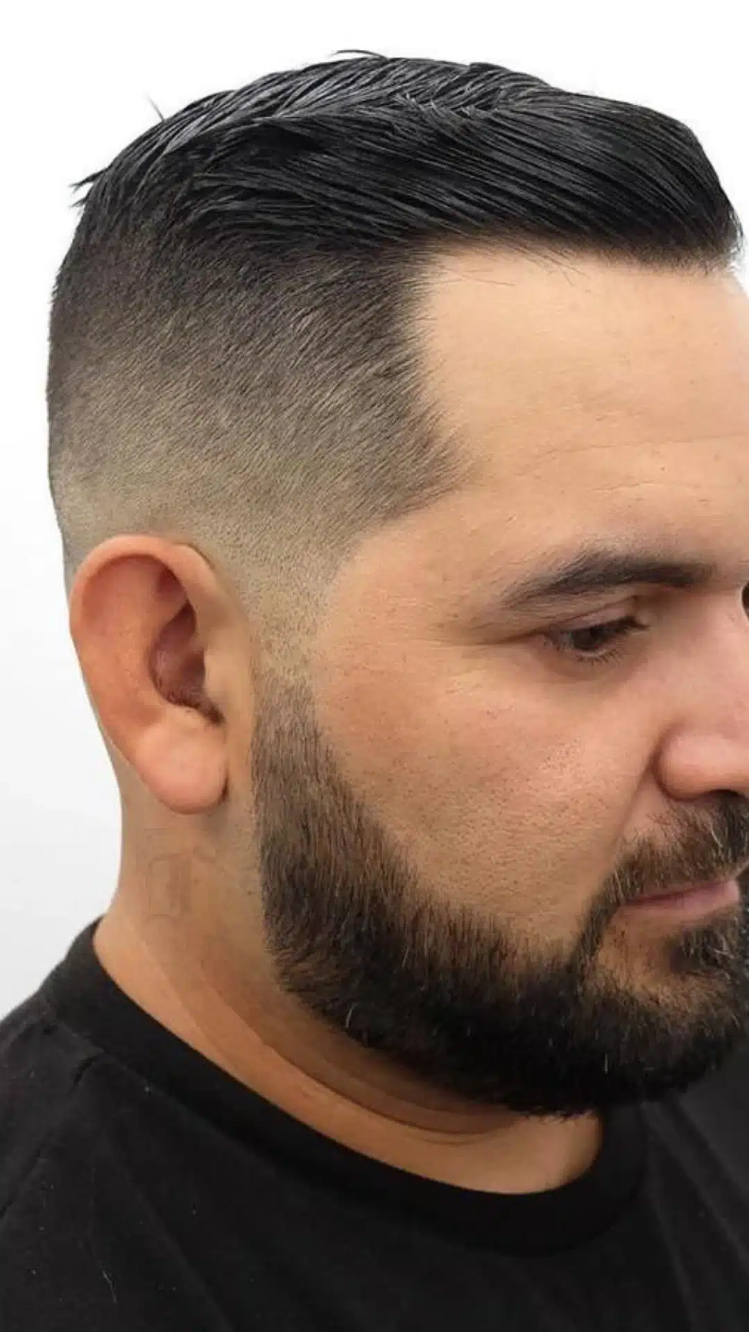 Slick side parted haircut with a clean low fade and full shaped beard shown in close side profile against a white background